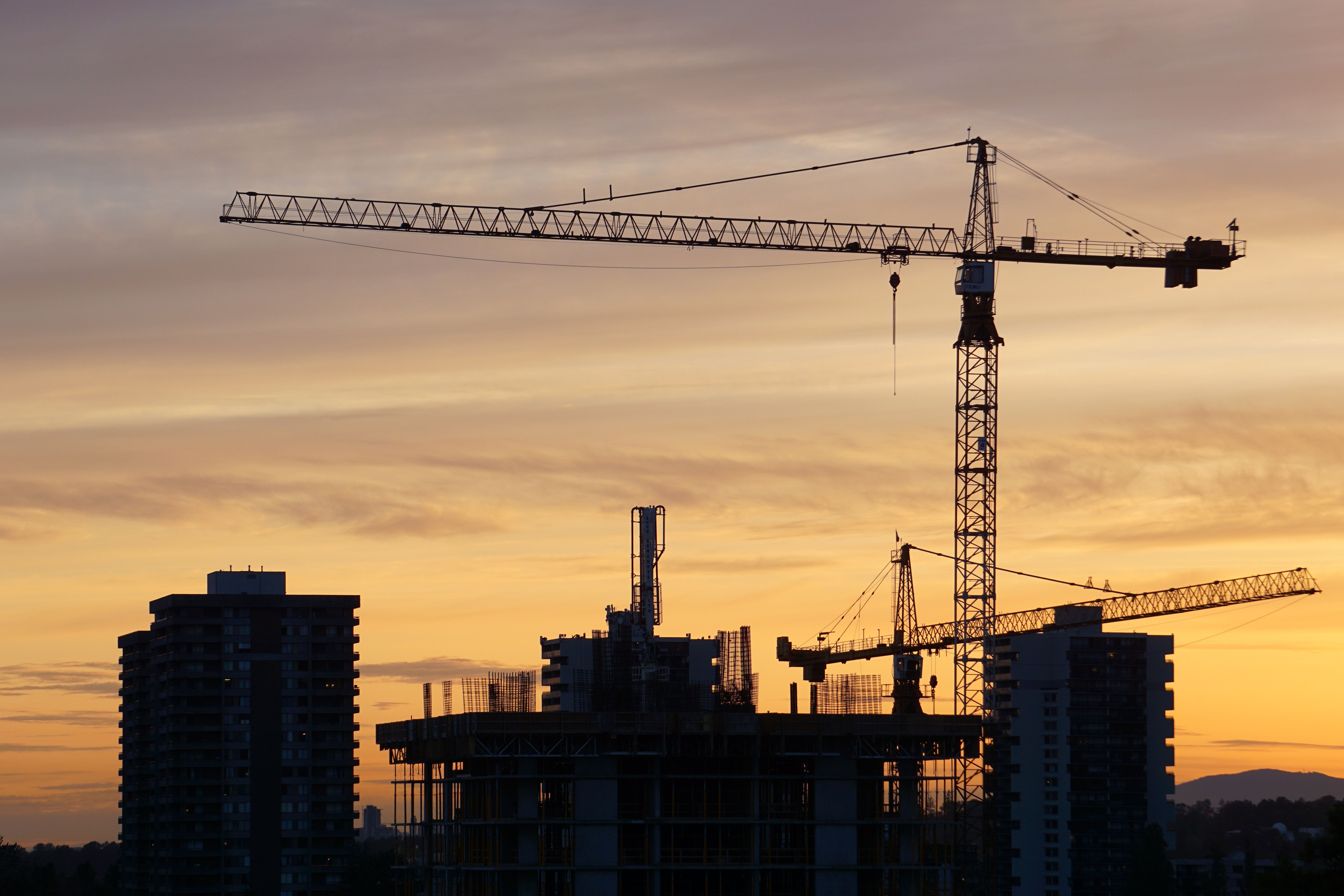 Tower cranes on an active construction site at dusk